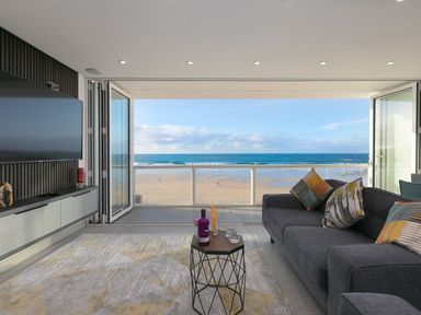 A living room with a sofa a coffee table and a television overlooking the beach at Louies Loft in St Ives