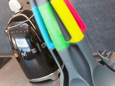 A black smeg kettle next to kitchen utensils with colored handles on a countertop at Louies Loft in St Ives
