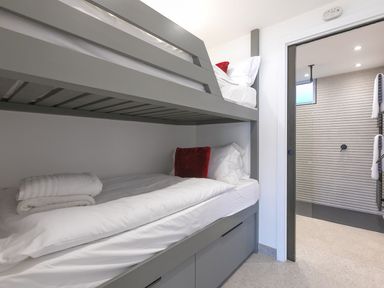 A bedroom with bunk beds and an open door leading to a bathroom at Louies Loft in St Ives
