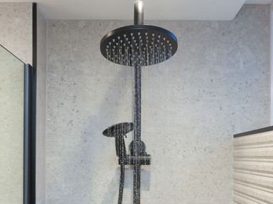 A bathroom shower with water running from a round black overhead showerhead at Louies Loft in St Ives