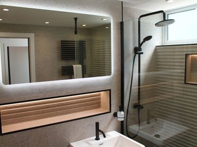 A bathroom with a sink and faucet a large illuminated mirror a walk in shower with a rainfall showerhead and handheld shower Louies Loft St Ives