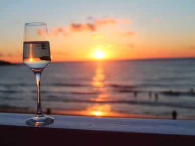 A glass of water on a railing with a sunset over the ocean in the background at Louies Loft in St Ives