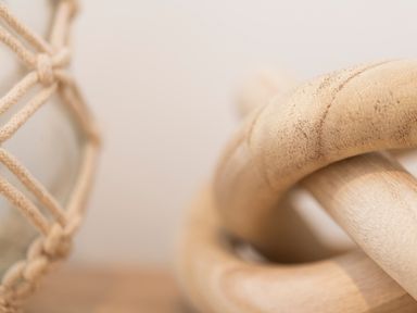 A close up of a wooden knot sculpture and a rope net basket on a surface at Maple Lodge in Angarrack
