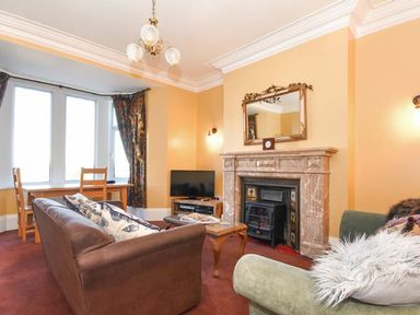 A living room with brown and green sofas a wooden coffee table a fireplace and a TV at Claremount in Alnmouth