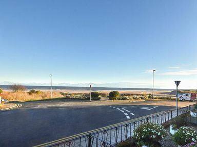A view of a road and beach with a clear sky and some plants at Claremount in Alnmouth