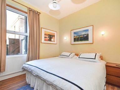 A bedroom with a double bed two framed pictures on the walls and beige curtains at Claremount in Alnmouth
