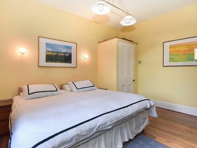 A bedroom with a double bed two framed pictures on the yellow walls and a closed door at Claremount in Alnmouth