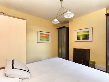 A bedroom with a bed pillow two framed pictures a dresser a wardrobe and a waste bin at Claremount in Alnmouth