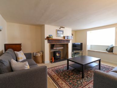 A living room with two gray sofas a black coffee table a fireplace and a bay window seat at 30 Fleet Street in Beaminster