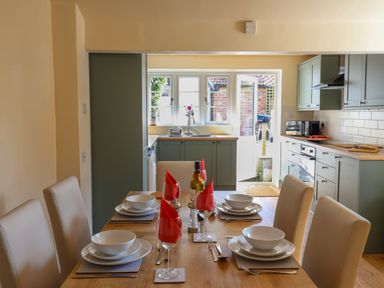 A dining table set for six in a kitchen with green cabinets and an open door at 30 Fleet Street in Beaminster