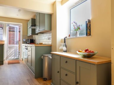 A kitchen with green cabinets a bowl of fruit and glasses on the counter at 30 Fleet Street in Beaminster