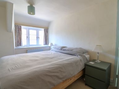 A bedroom with a bed beside a window and a bedside table with a lamp at 30 Fleet Street in Beaminster