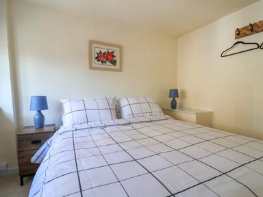 A bedroom with a double bed with checkered bedding two blue lamps on nightstands and a floral painting on the wall at 30 Fleet Street in Beaminster