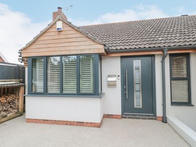Front entrance of a house with a blue door and windows with shutters at Orchard Leigh in North Petherton