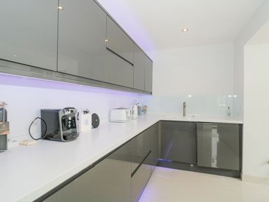 A kitchen with grey cabinets coffee machine toaster kettle and under cabinet lighting at Orchard Leigh in North Petherton