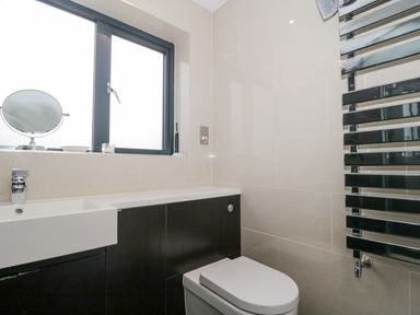 A bathroom with a toilet sink window and a heated towel radiator at Orchard Leigh in North Petherton