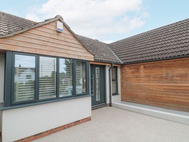 An exterior view of a house entrance with wooden cladding windows and a gray door at Orchard Leigh in North Petherton