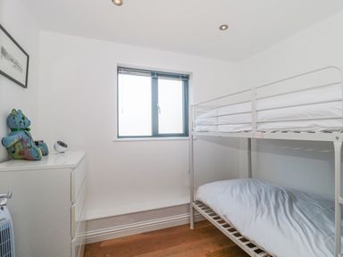 A small bedroom with a bunk bed a white dresser with a teddy bear and a window at Orchard Leigh in North Petherton