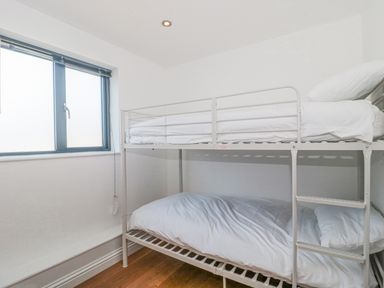 A small bedroom with a white bunk bed and a window with blinds at Orchard Leigh in North Petherton
