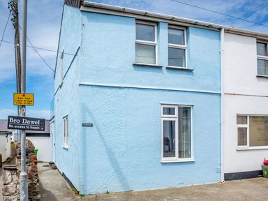 A blue two-story building with windows and a sign reading Victoria House with a signpost nearby saying Bro Dawel no access to beach at Victoria House in Rhosneigr
