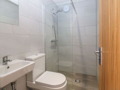 A bathroom with a white toilet and sink next to a glass enclosed shower at Victoria House in Rhosneigr