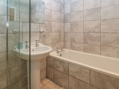 A bathroom with a pedestal sink a bathtub and tiled walls at Victoria House in Rhosneigr