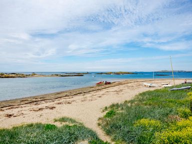 A sandy beach with small boats and grassy area by the sea at Victoria House in Rhosneigr
