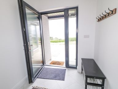 An entrance hallway with an open glass door a black bench and wall hooks at Ballyness Bay in Killult Upper near Gortahork County Donegal