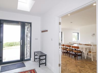 An entrance area with glass door and bench next to a dining room with a long table and chairs at Ballyness Bay in Killult Upper near Gortahork County Donegal