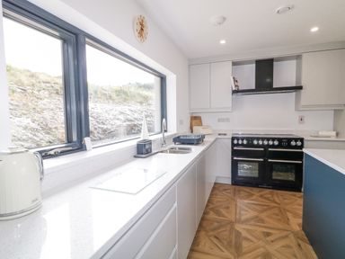 A kitchen with white countertops a black stove a large window and wooden patterned floor at Ballyness Bay in Killult Upper near Gortahork County Donegal