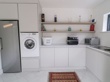 A kitchen with a washing machine microwave oven sink and shelves above the counter with bottles and decorative items at Ballyness Bay in Killult Upper near Gortahork County Donegal