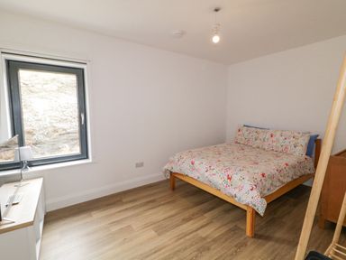 A bedroom with a bed floral bedspread a window and a cabinet with a television at Ballyness Bay in Killult Upper near Gortahork County Donegal