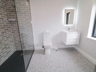 A bathroom with a walk-in shower a toilet a wall-mounted sink with a lit mirror and a window at Ballyness Bay in Killult Upper near Gortahork County Donegal