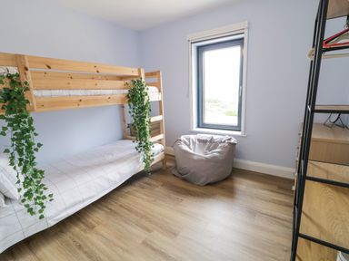 A bedroom with a wooden bunk bed with plants and a bean bag chair by a window at Ballyness Bay in Killult Upper near Gortahork County Donegal