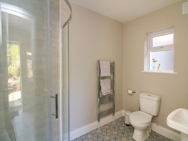 A bathroom with a shower enclosure a toilet a sink a towel rack and a window at An Teach Ban in Bunclody County Wexford