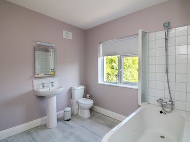 A bathroom with a pedestal sink toilet bathtub shower and window at An Teach Ban in Bunclody County Wexford