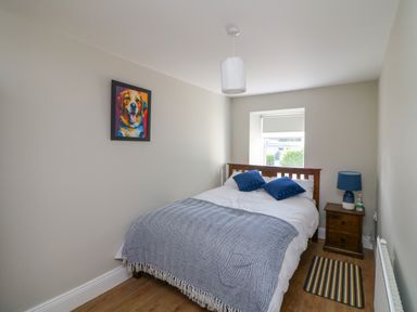 A bedroom with a bed with blue pillows a bedside table with a blue lamp and a window at An Teach Ban in Bunclody County Wexford