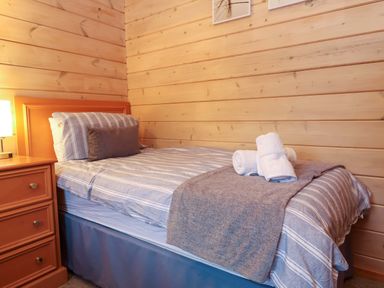 A bedroom with a bed, bedside table, and towels at Elderberrys Lodge in Bideford