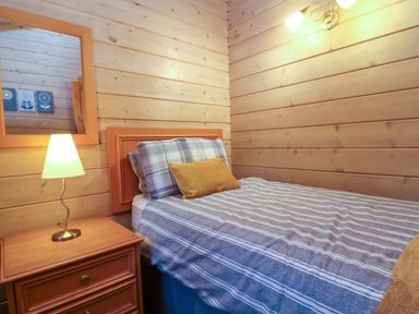 A bedroom with a bed and nightstand at Elderberrys Lodge in Bideford