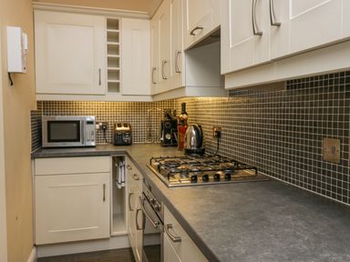 A kitchen with cabinets countertop gas stove microwave toaster kettle and coffee machine at Ramblers Lodge Bowland Bridge near Bowness-On-Windermere Lake District