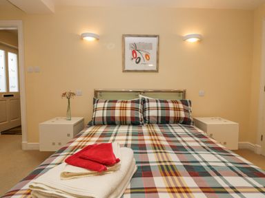 A bedroom with a plaid bedspread on a double bed with folded towels on top and nightstands on each side at Ramblers Lodge in Bowland Bridge near Bowness-On-Windermere Lake District