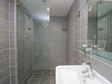 A shower area with gray tiles and a white sink with a faucet and glass shelf in a bathroom at Ramblers Lodge Bowland Bridge near Bowness-On-Windermere Lake District