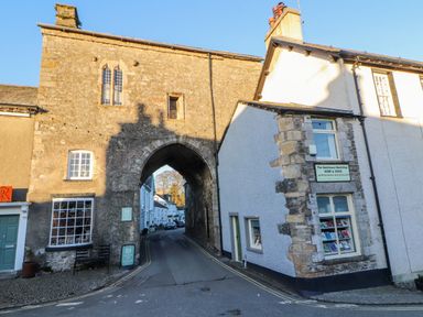 A street scene with an old stone archway and buildings including a bookshop in Bowland Bridge near Bowness-On-Windermere Lake District