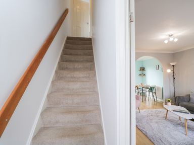 A staircase leading to an upper floor with a view of a living area at 20 Honeycroft Bourton-On-The-Water
