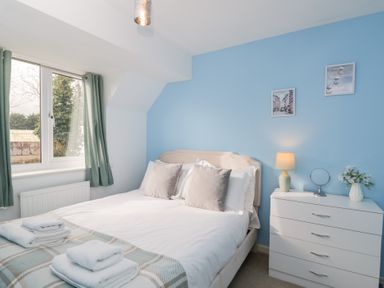 A bedroom with a bed, bedside lamp, and chest of drawers at 20 Honeycroft in Bourton-On-The-Water