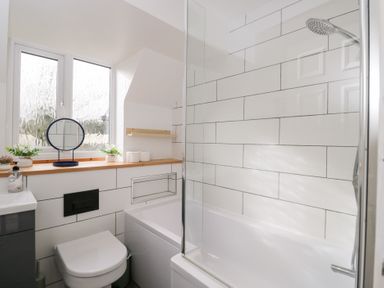 A bathroom with a bath, shower, and sink at 20 Honeycroft, Bourton-On-The-Water