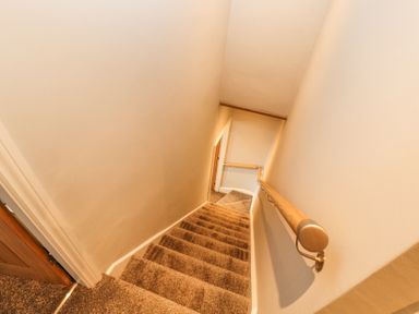 A carpeted staircase with wooden handrails along the walls at Grace House in Silloth