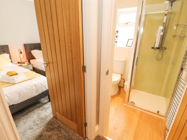 A bedroom with two beds and a bathroom with a shower and toilet at Grace House in Silloth