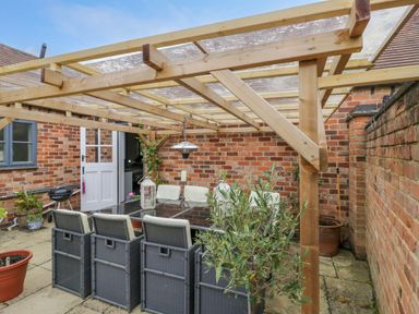 An outdoor covered patio with a table and chairs against brick walls at The Bit on the Side in Ettington