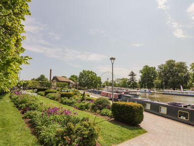 A riverside park with flower beds boats on the water and a ferris wheel in the background at The Bit on the Side in Ettington